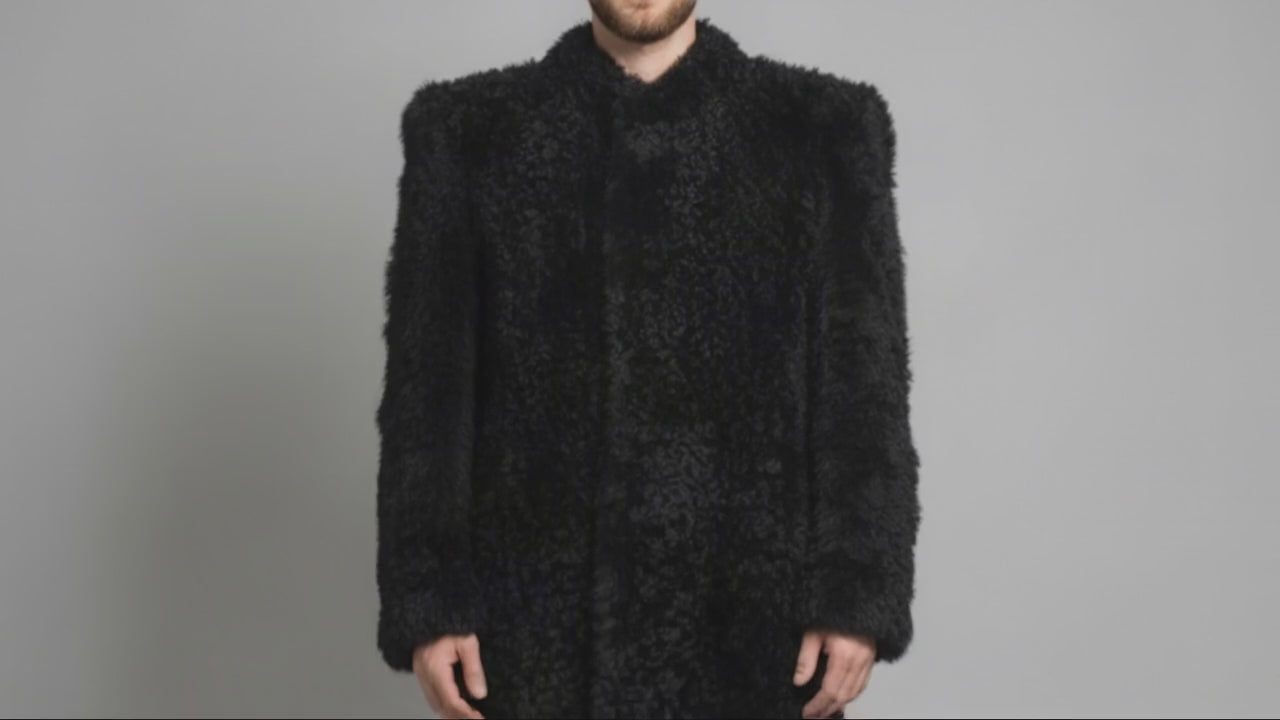 Man wearing the black Bishop Tigrado shearling coat opens the front to reveal its satin lining, interior pockets, and a hand-painted shirt.